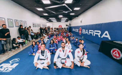 Youth martial arts practitioners drilling guard passes on academy mats.